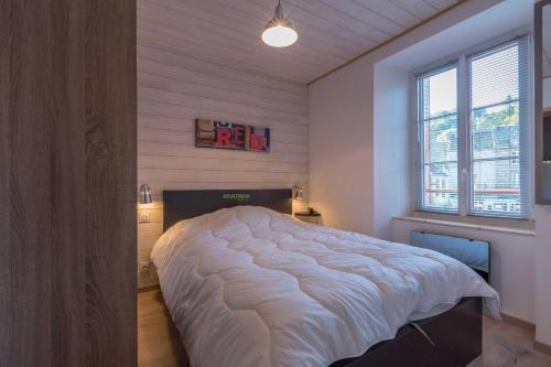 a bedroom with a large bed and a window at Le Petit Lutess in Murol