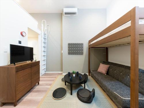 a living room with a couch and a tv at TRIP POD TOJIN-MACHI A in Fukuoka