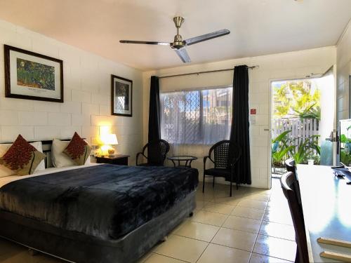 South Cairns Resort في كيرنز: غرفة نوم مع سرير ومروحة سقف