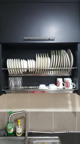 a shelf filled with plates and dishes in a kitchen at TINGKAT 21/10, PANGSAPURI LADANG TOK PELAM in Kuala Terengganu