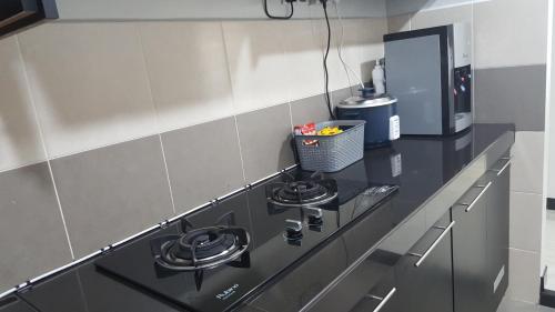 a kitchen with a black stove and a microwave at TINGKAT 21/10, PANGSAPURI LADANG TOK PELAM in Kuala Terengganu