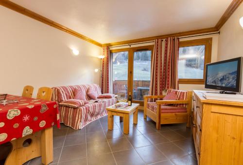 a living room with a couch and a tv at Résidence Le Critérium in Lanslebourg-Mont-Cenis