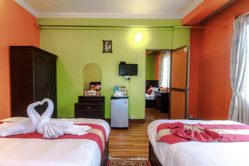 a bedroom with two beds and a desk at Hotel Nepalaya in Kathmandu