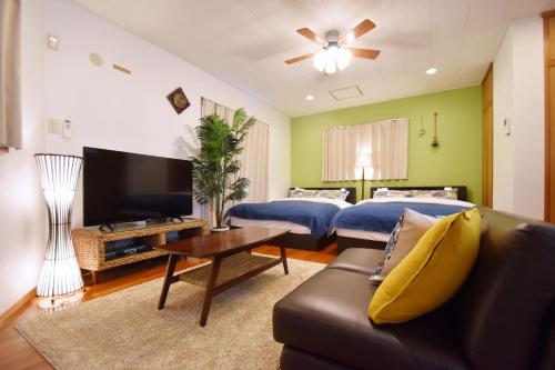 a living room with two beds and a couch at Guest House Tsukishiro in Nanjo