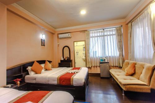 a bedroom with two beds and a couch and a chair at Hotel Nepalaya in Kathmandu