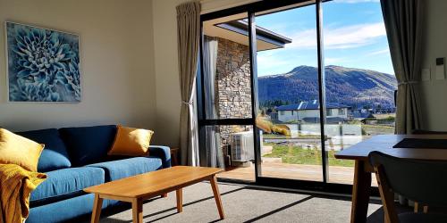 a living room with a blue couch and a large window at Skyblue Tekapo in Lake Tekapo