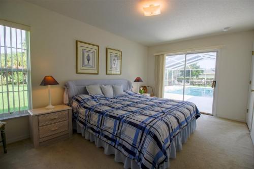 a bedroom with a bed with a blue and white blanket at Luxury 2BR-3BA Pool Villa and 20 Min to WEC- Ocala in Inverness