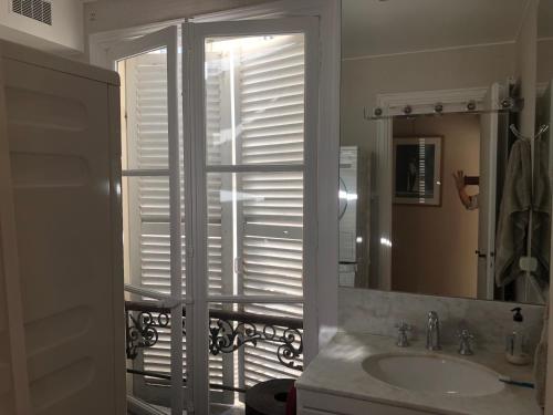 a bathroom with a sink and a window with shutters at 100m2 flat appartement d'artiste in Paris