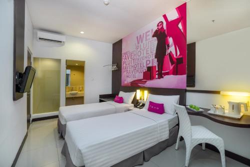 Habitación de hotel con 2 camas y pared de color rosa en favehotel Pluit Junction, en Yakarta