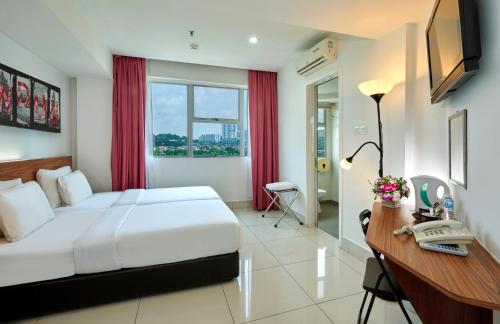 una camera d'albergo con letto e scrivania con telefono di V Hotel Kuala Lumpur a Kuala Lumpur