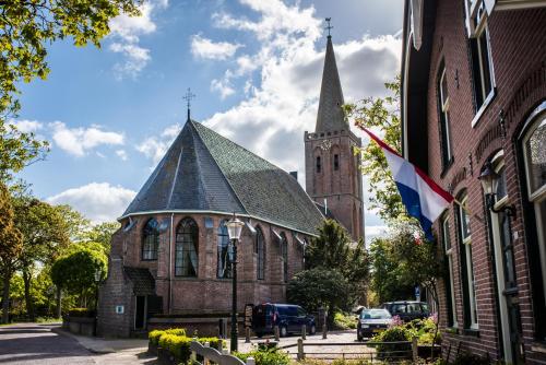 a church with a steeple and a flag on a building at B&B Appartement Hemels in Twisk
