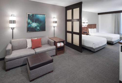 um quarto de hotel com um sofá e uma cama em Hyatt Place Jacksonville Airport em Jacksonville