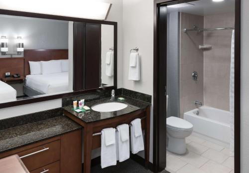 a bathroom with a sink and a toilet and a mirror at Hyatt Place Jacksonville Airport in Jacksonville
