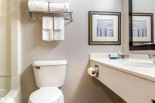 a bathroom with a toilet and a sink with towels at Rodeway Inn Denver Downtown in Denver
