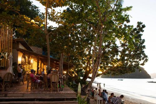 a group of people sitting at a restaurant on the beach at Maremegmeg Beach Club in El Nido
