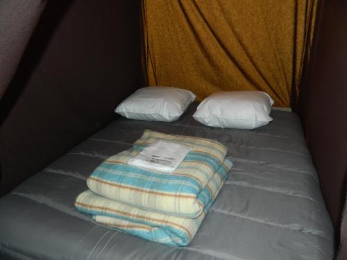 a bed with a blanket and two pillows on it at Oh! Campings La Brise in Saintes-Maries-de-la-Mer