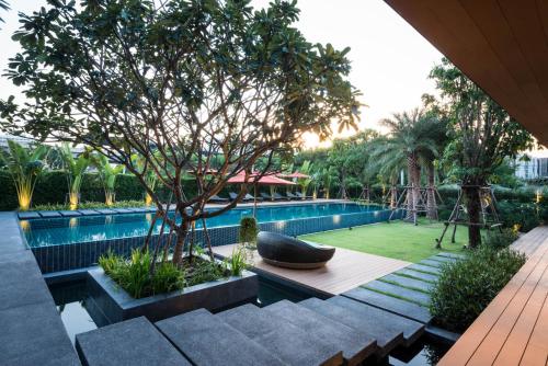 a pool with a black bowl sitting on a bench next to a tree at The Silver Palm Wellness Resort in Bangkok