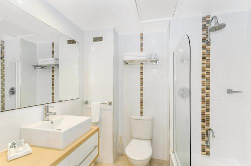 a white bathroom with a toilet and a sink at Aquarius On The Beach in Townsville