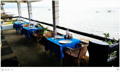 a row of blue tables and chairs with a view of the water at Love's Beach & Dive Resort in Moalboal