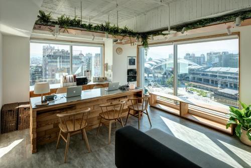 um quarto com um bar com cadeiras e janelas em Norden Ruder Hostel Taichung em Taichung