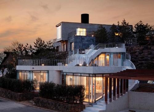 une grande maison avec un escalier en colimaçon en face de celle-ci dans l'établissement Lotte Resort Jeju Artvillas, à Seogwipo