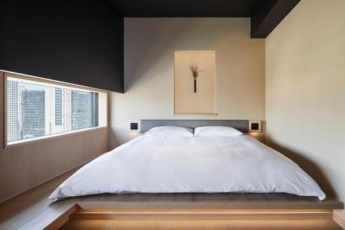 a bedroom with a large white bed and a window at ONSEN RYOKAN YUEN SHINJUKU in Tokyo