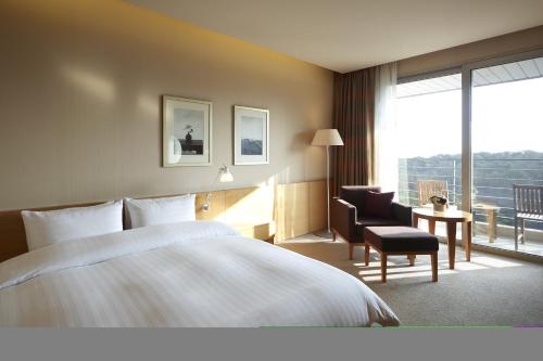 um quarto de hotel com uma cama e uma cadeira e uma janela em Rolling Hills Hotel em Hwaseong