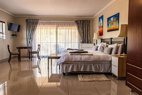a bedroom with a bed and a table and a desk at Tinyiko Kruger Lodge in Marloth Park