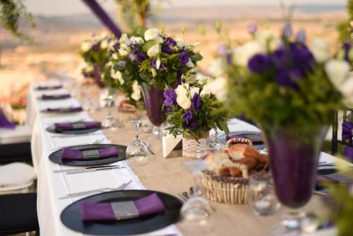 a long table with purple and white flowers in vases at Eyes Of Cappadocia Cave Hotel in Uchisar