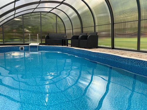 a large swimming pool in a greenhouse with a swimming pool at Apartmány Na Faře in Bílá