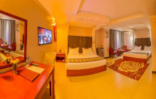 カンパラにあるRussell Hotelのベッド2台とデスクが備わるホテルルームです。