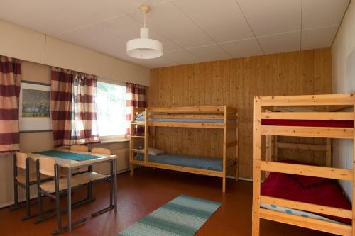 Cette chambre comprend 2 lits superposés et une table. dans l'établissement Nikkilän Elämyskylä, à Saariharju