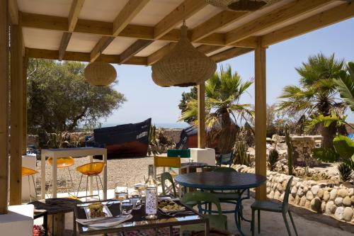 un patio con mesa y sillas en la playa en Riad Tamayourt Ocean View & piscine chauffée à 30, en Essaouira