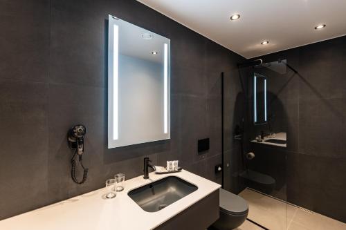 a bathroom with a sink and a mirror and a toilet at Maestro Design Hotel in Liepāja
