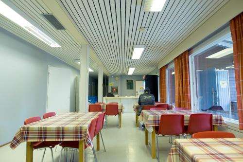 une cafétéria avec des tables et des chaises et un homme assis à une table dans l'établissement Nikkilän Elämyskylä, à Saariharju