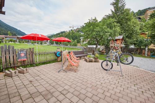 a patio with umbrellas and chairs and a bike at Ski & Bike Appartements Forsthaus in Saalbach Hinterglemm