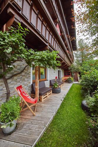 a patio with a red chair and a bench at Ski & Bike Appartements Forsthaus in Saalbach Hinterglemm