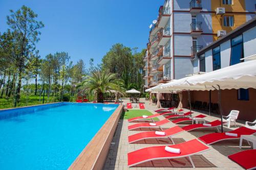 a pool with lounge chairs and umbrellas next to a building at Iveria Elli Hotel in Shekvetili