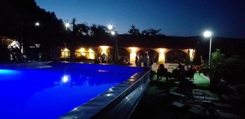 a swimming pool at night with people sitting around at Cabana Plapumioara in Eşelniţa