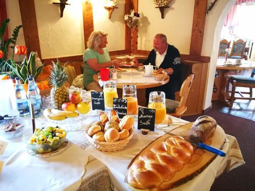 een groep mensen die aan een tafel zitten met brood en fruit bij Gästehaus-Pension Keiss in Hopferau