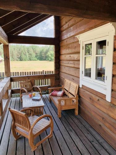 a porch of a wooden cabin with a table and chairs at Vila Migla in Pašekščiai