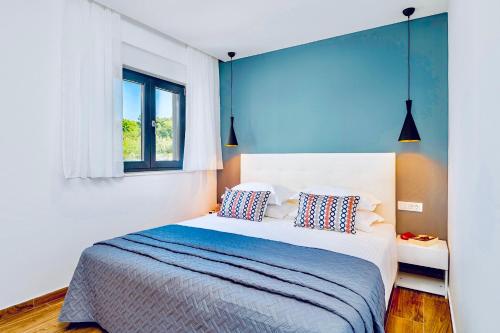 um quarto com uma cama com paredes azuis e uma janela em Stella Apartment em Cavtat