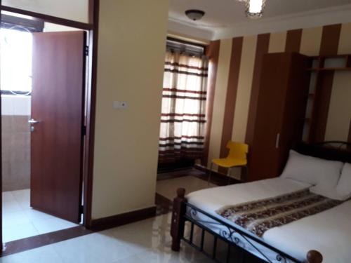 a bedroom with a bed and a door and a yellow chair at Egret Pilgrims Inn in Kampala