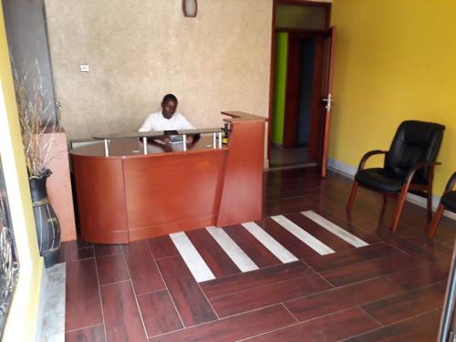 a man sitting at a counter in a lobby at Egret Pilgrims Inn in Kampala