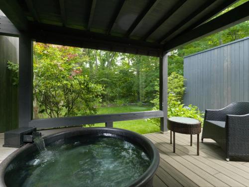 a hot tub on a deck with a table and a chair at Hakodate Onuma Tsuruga Resort EPUY- 30km from Hakodate Station in Hakodate