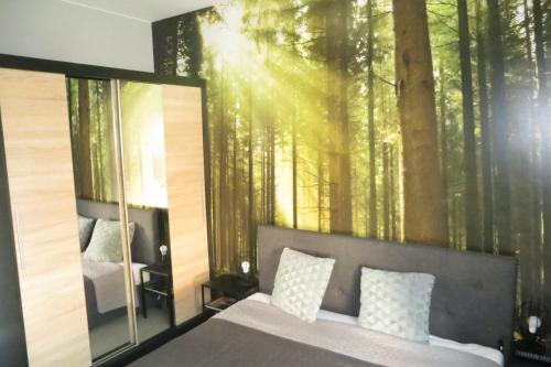 Apartament MODERN z ogrodem في شكلارسكا بوريبا: غرفة نوم بسرير وجدارية غابة