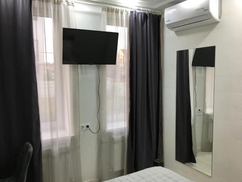 a bedroom with a tv and a window with curtains at Moonlight Hotel in Chişinău