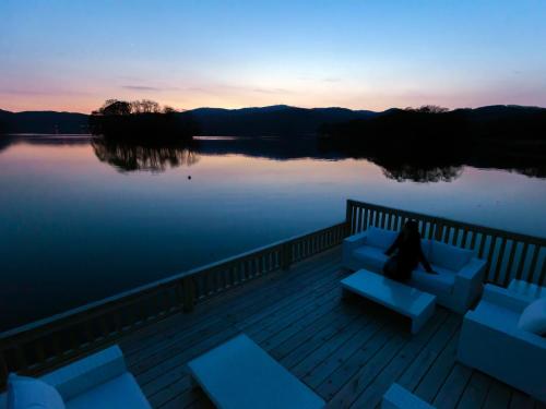 a person sitting on a couch on a deck overlooking a lake at Hakodate Onuma Tsuruga Resort EPUY- 30km from Hakodate Station in Hakodate