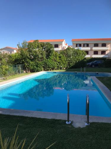 una grande piscina blu di fronte a un edificio di Casa Braites T3 Soltroia Mar - Ar Condicionado - 5 minutos a pé da praia e a 12Km da Comporta a Tróia