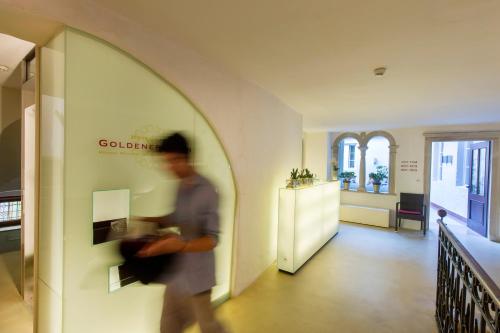 a man walking down a hallway in a building at Hotel Goldener Stern in Caldaro